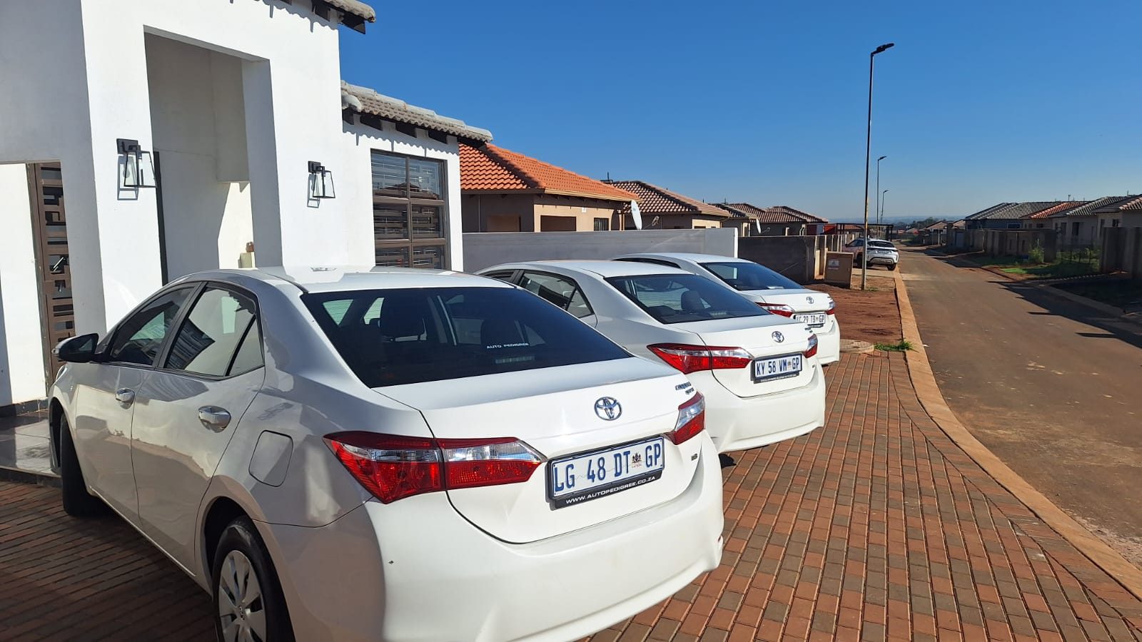 Three white Toyota Corolla sedans parked outside Ahifambi base